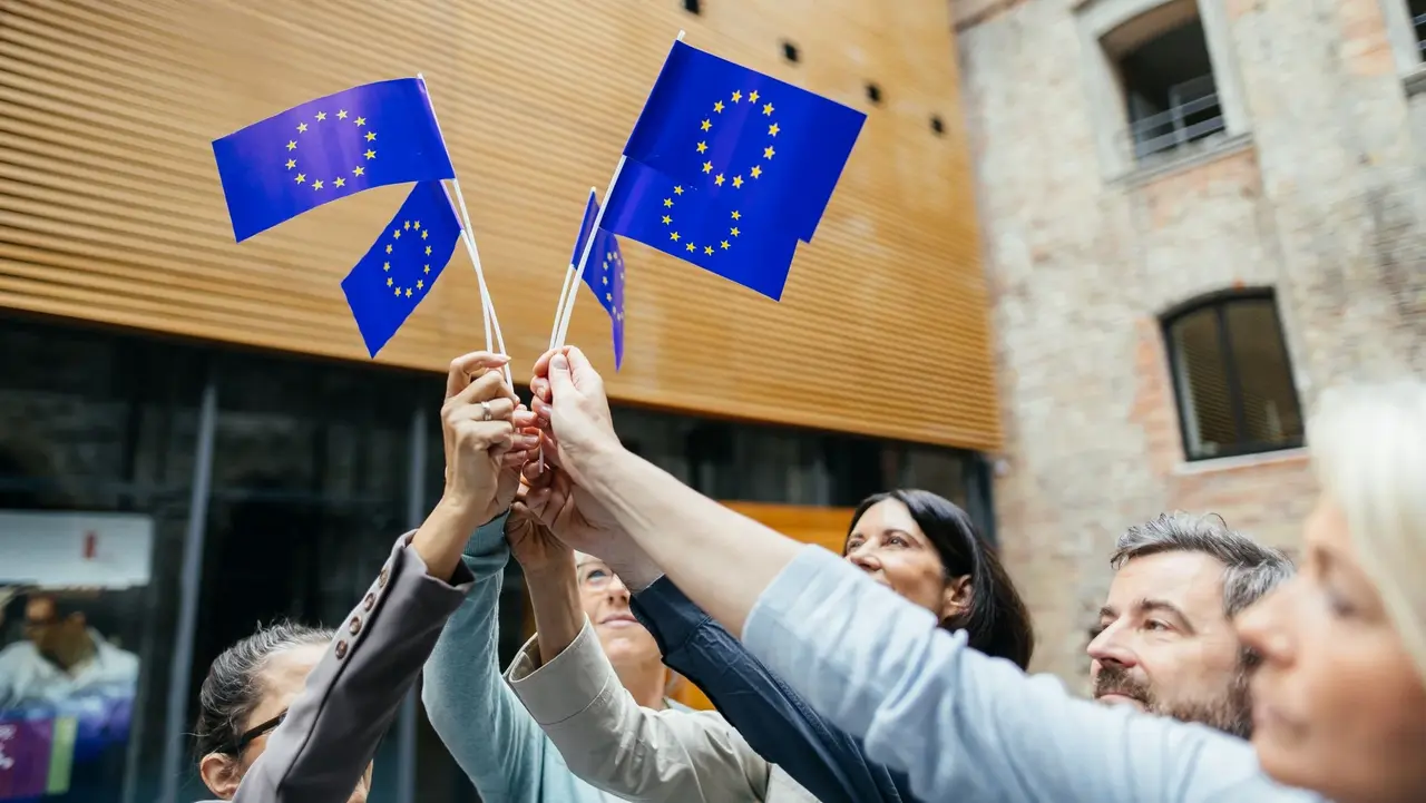 Menschen halten gemeinsam Europafahnen in die Luft.